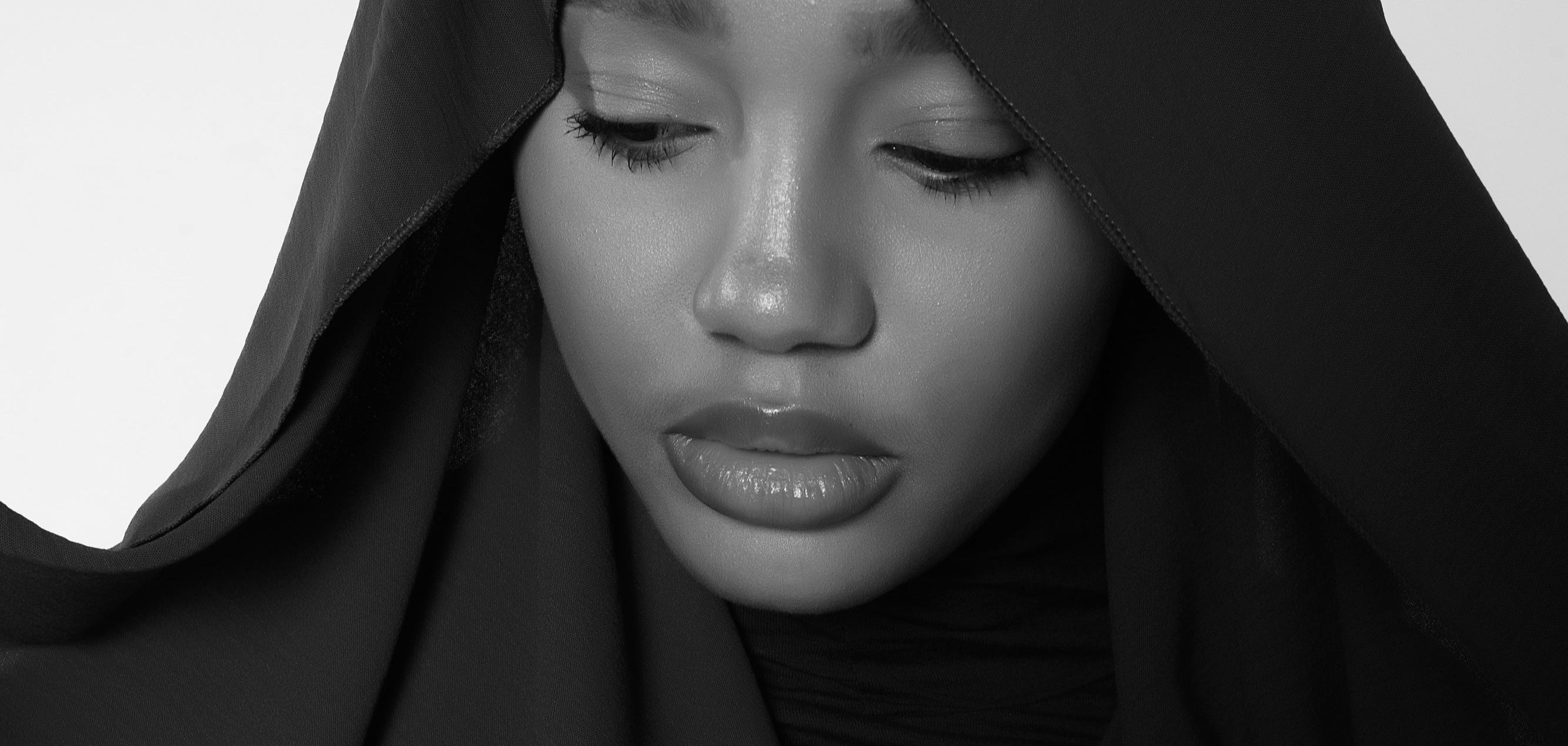 Black and white close-up of a person wearing a headscarf.